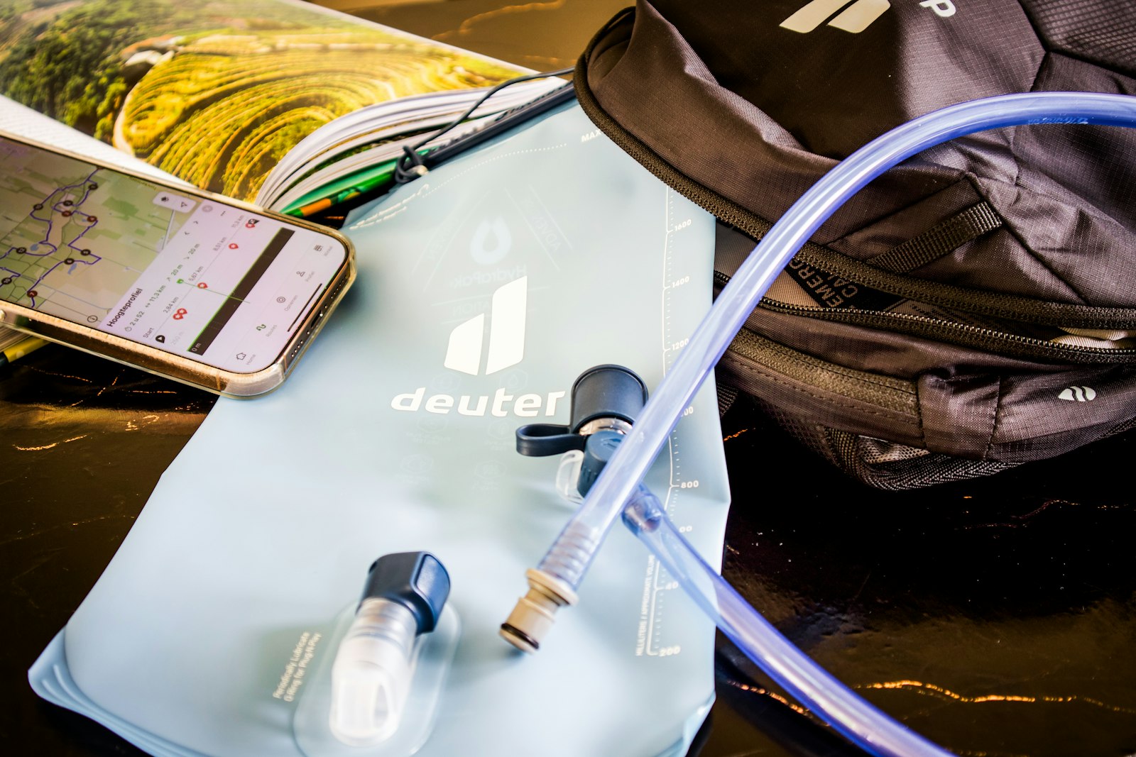 Hiking kit laid out on wood: waterproof jacket, boots, daypack, map, water bottle and first aid kit